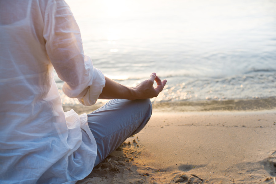 Woman meditating on beach in lotus position